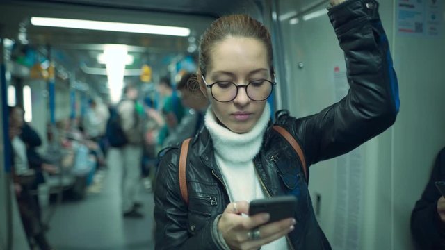 Woman on a subway train looking at a smartphone