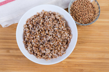 Top view of prepared buckwheat porridge and uncooked buckwheat groat