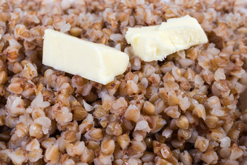 Buckwheat porridge with butter pieces close-up in selective focus
