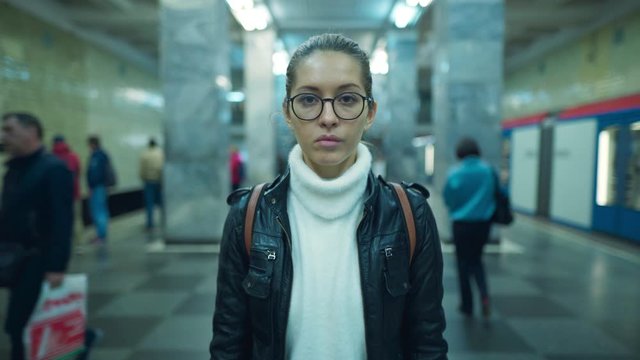 Portrait of woman standing on a subway platform looking straight at the camera