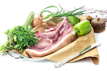Piece of raw pork and vegetables on a white background