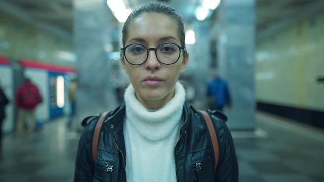 Portrait of woman standing on a subway platform looking straight at the camera