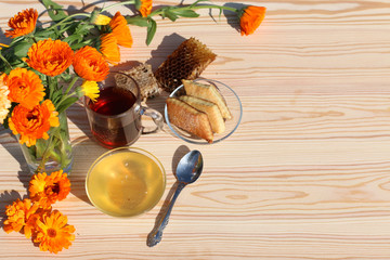 Honey, tea and wild orange flowers on a wooden background