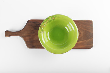 An empty green saucer on a white background on a wooden board