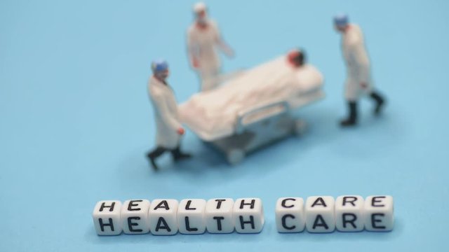 Miniature medical toy people - Health care sentences with blue or teal background-out of focus (oof) to sharp focus.