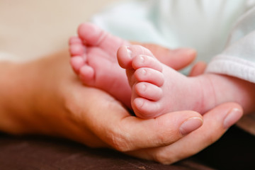 Obraz na płótnie Canvas Main d'une mère tenant les petits pieds de son bébé