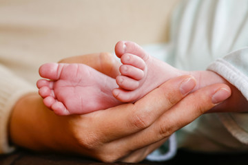 Main d'une. m&egrave;re qui tient les pieds de son b&eacute;b&eacute;