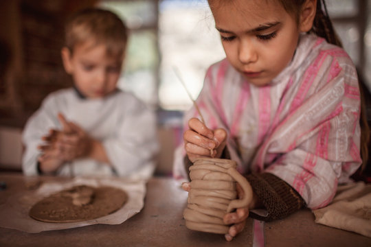 Cute little kids playing together with modeling clay in pottery workshop, craft and clay art