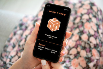 female hands holding phone with app tracking delivery package