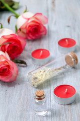 Fototapeta na wymiar Pink roses, oil bottles and candles on a gray wooden table. March 8. Valentine's Day. Greeting card. Romantic and beautiful background. Spa treatments. Personal care. Love and beauty.