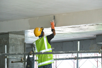 Site workers are doing soffit skim coat work at the construction site. 