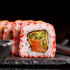 Sushi with chopsticks and soy sauce on a stone board. Japanese food. Set of sushi roll with vegetables, fish and caviar.