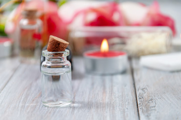 Pink roses, oil bottles and burning candles on a gray wooden table. March 8. Valentine's Day. Greeting card. Romantic and beautiful background. Spa treatments. Personal care. Love and beauty.