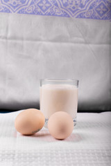 A glass of milk with raw eggs isolated on white background