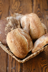 Assortment of baked bread on wooden table background. Bread background, top view of white, black and rye loaves. Healthy food. 