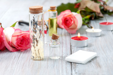 Pink roses, oil bottles and burning candles on a gray wooden table. March 8. Valentine's Day. Greeting card. Romantic and beautiful background. Spa treatments. Personal care. Love and beauty.