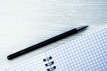 Notebook on a spiral and pen on a white background with golden veins. Copy space
