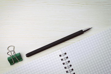 Spiral notebook, pen and stationery paper clip on a white background with golden streaks. Copy space