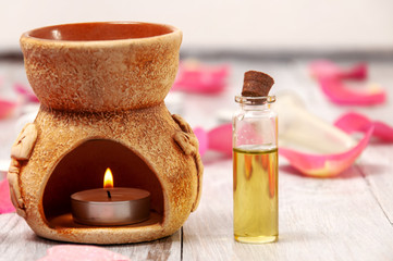 Obraz na płótnie Canvas Aroma lamp with a burning candle and essential oils, pink salt bath bomb in the form of a heart, rose petals on a gray wooden table. Face and body care. Spa treatments.