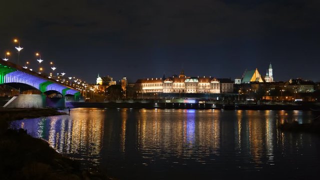 River view of Warsaw city by night in Poland with glittering lights reflection in water, illuminated Royal Castle in the Old Town