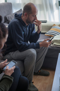 Hombre pensativo mirando el movil nada mas despertarse en el sofa de su casa