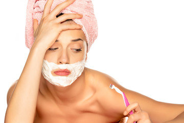 Young disappointed woman shaves her face