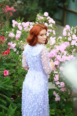 Naklejka premium beautiful red-haired girl in arranger where azalea blooms in a colorful flying dress