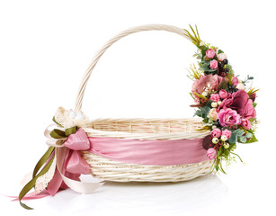 Fototapeta na wymiar Original wicker basket with a beautiful, delicate pink decor with a pink ribbon around the basket. On a white background.