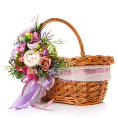 Fototapeta na wymiar Easter basket. Brown wicker basket with colorful floral decor and colored ribbons on a white background.