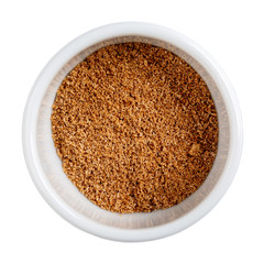 Ground nutmeg isolated on white. Freshly grated spice in white bowl. Close-up, top view.