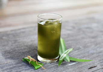 Pandan (Pandanus amaryllifolius) ice cool tea with green leaves on wooden table, herbal soft drink