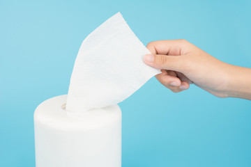 Female hand pull tissue paper isolated on blue background
