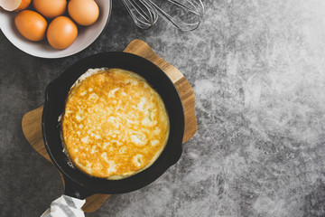 Omelette in black skillet pan, dark food photo. Top view of fresh breakfast. Copy space.