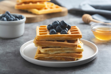 Stack of belgian waffles with blueberry and honey for breakfast. Delicious homemade pastry. Copy space.