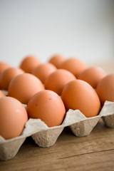 Hen eggs in paper carton box on background table. Organic products from farm. Copy space. Breakfast menu concept. 