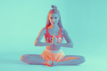 Athletic young woman doing yoga exercise. Neon lights
