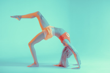 Athletic young woman doing yoga exercise. Neon lights