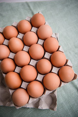 Hen eggs in paper carton box on background table. Organic products from farm. Copy space. Breakfast menu concept. 