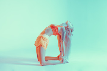 Athletic young woman doing yoga exercise. Neon lights