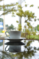 white cup of hot coffee drink put on glass table in cafe