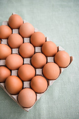 Hen eggs in paper carton box on background table. Organic products from farm. Copy space. Breakfast menu concept. 