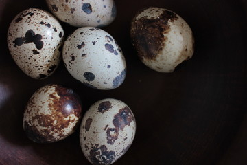 Closeup of quail eggs in a brown ceramic bowl. Top view