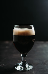 Freshly brewed dark beer on the black rustic background. Selective focus. Shallow depth of field.