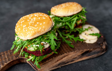 two vegetarian burger with beets, chickpeas, pear, arugula, cucumber on a cutting board on a stone background