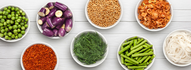 varieties of ingredients in bowls on white wooden background