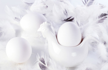 White natural eggs and white feathers. Monochrome, minimal. Happy easter concept.