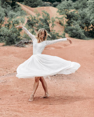 Fototapeta na wymiar young woman in white dress spinning