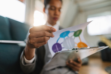 Close-up of black businesswoman analyzing chart at home office.