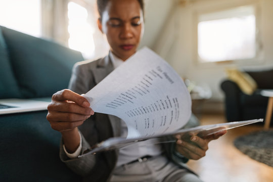 Close-up of African American businesswoman analyzing paperwork at home.