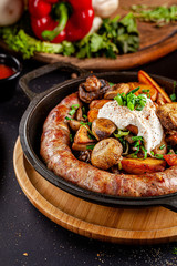 Turkish oriental cuisine. Homemade sausage, with fried mushrooms, green onions, and kaimak sauce. Serving dishes in restaurant in a cast-iron pan. background image, copy space text